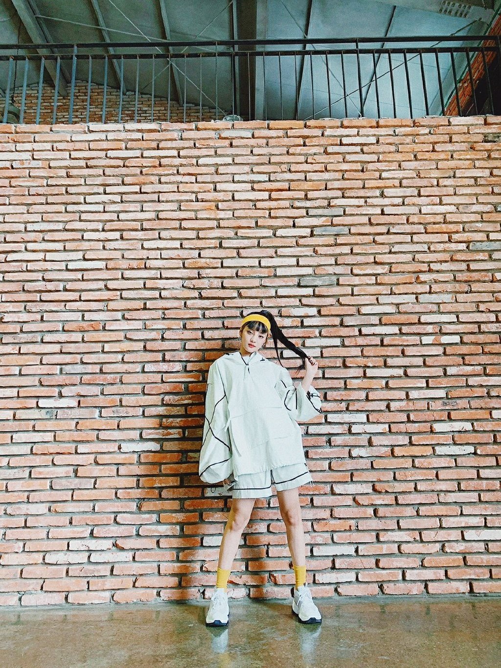 她是组合梦幻主唱，穿白底黑线休闲套装，发带增加运动感