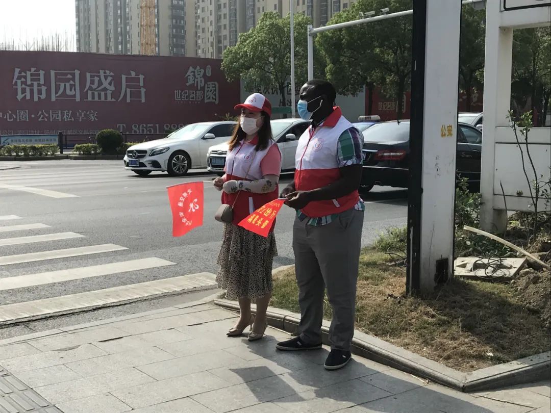 啥情况?江都街头有个黑人小哥,穿着红白相间的马甲,举起小红旗