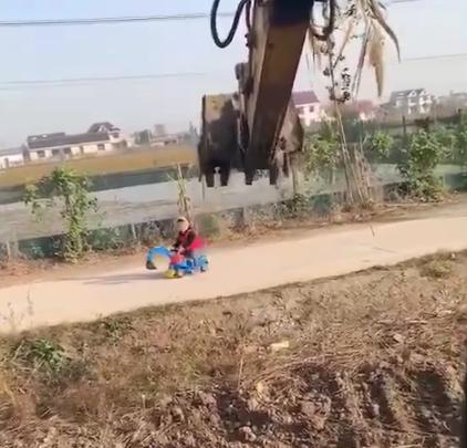 小男孩开大型挖掘机干活,男孩开着挖掘机